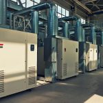 A large-scale industrial air compressor installed in a manufacturing plant, connected to multiple pneumatic tools.